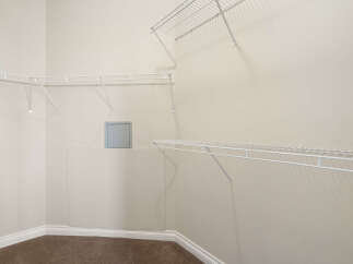 This spacious walk-in closet features ample white wire shelving installed along the walls, offering versatile storage solutions.