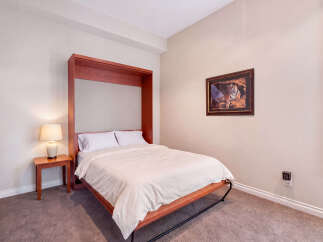 This bedroom features a convenient murphy bed with a rich wooden frame, perfect for maximizing space.