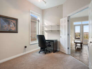 This home office space features a comfortable black leather executive chair paired with a sleek dark desk, perfect for productivity.
