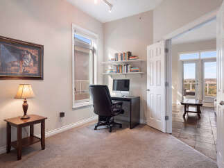 This home office features a comfortable leather executive chair in front of a dark wood desk with a computer and shelves stocked with books.