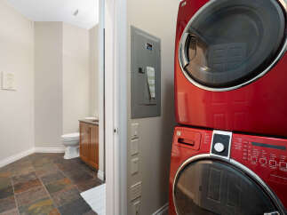 This modern bathroom features a stacked red washer and dryer unit, perfect for maximizing space.