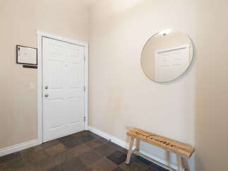 Step into a welcoming entryway featuring a classic white door and a stylish round mirror.