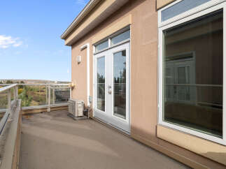 Enjoy the outdoors from this spacious balcony with a glass railing, offering a scenic view of the surrounding landscape.