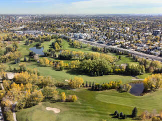 Experience the best of urban living with this stunning aerial view showcasing a vibrant cityscape adjacent to a meticulously maintained golf course.