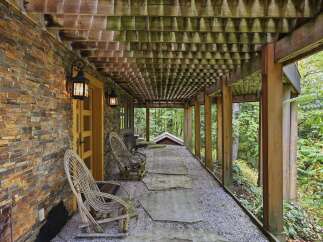 Experience the charm of this rustic covered porch, featuring a natural stone accent wall and a wooden slatted ceiling that creates a unique architectural detail.