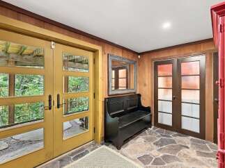 Step into a welcoming entryway featuring a bright yellow double door with glass panels that offer views of lush greenery.