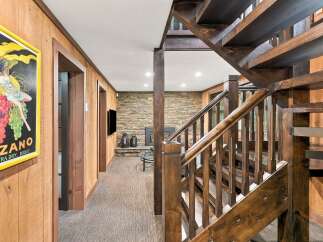Step into a rustic retreat featuring a stunning wooden staircase and a cozy living area with a stone accent wall and fireplace.