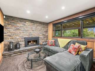 Cozy up by the stone fireplace in this inviting living room, perfect for relaxing evenings.
