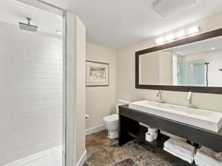 This modern bathroom features a spacious walk-in shower with white subway tile and a rainfall showerhead.