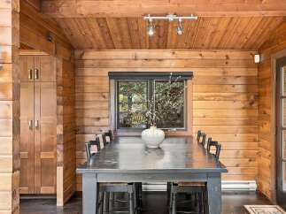 Experience rustic charm in this dining room, featuring warm wood-paneled walls and a vaulted wood-beamed ceiling.