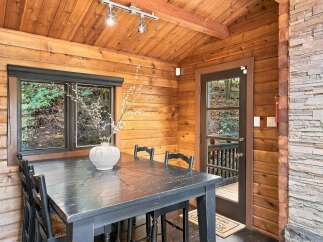 Enjoy rustic charm and cozy dining in this inviting screened porch, perfect for enjoying nature's beauty.