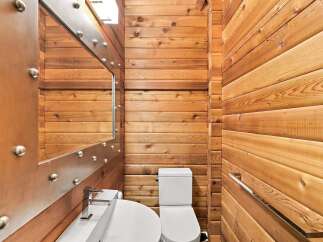 Experience rustic charm in this cozy bathroom, featuring warm wood-paneled walls and a sleek modern sink with a chrome faucet.