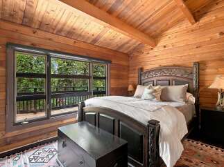Experience rustic charm in this cozy log cabin bedroom, featuring a grand wooden bed with ornate carvings and plush bedding.