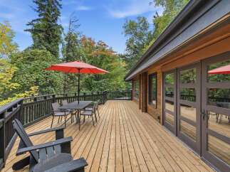 Enjoy the crisp autumn air on this expansive wooden deck, perfect for outdoor dining or relaxing.