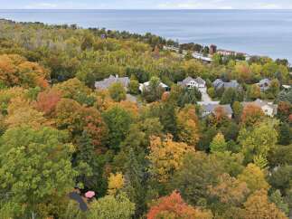 Experience the beauty of autumn from this stunning aerial view of a lakeside property.