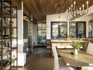 Experience modern rustic charm in this stunning kitchen and dining area, featuring a warm wood-paneled ceiling and expansive windows that flood the space with natural light.