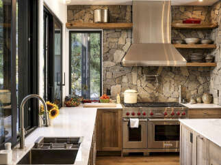 Experience rustic elegance in this stunning kitchen, featuring a striking stone accent wall that adds warmth and texture.