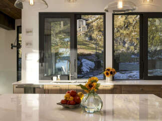 Experience breathtaking natural beauty from this stunning kitchen, featuring expansive windows that frame a picturesque landscape of rocky hillsides and serene waters.