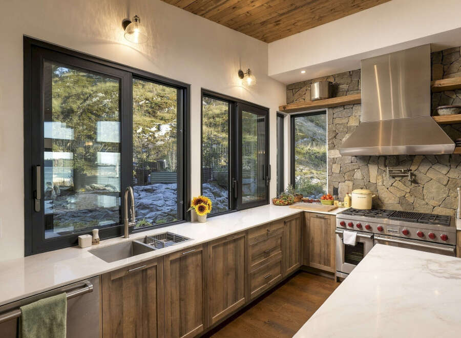 Experience modern living with this stunning kitchen featuring a large stainless steel range and hood, complemented by a stone accent wall.