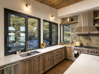 Experience modern living with this stunning kitchen featuring a large stainless steel range and hood, complemented by a stone accent wall.
