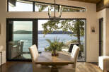 Experience breathtaking waterfront living in this stunning dining area, featuring expansive floor-to-ceiling windows that offer panoramic views of the serene water and lush greenery.