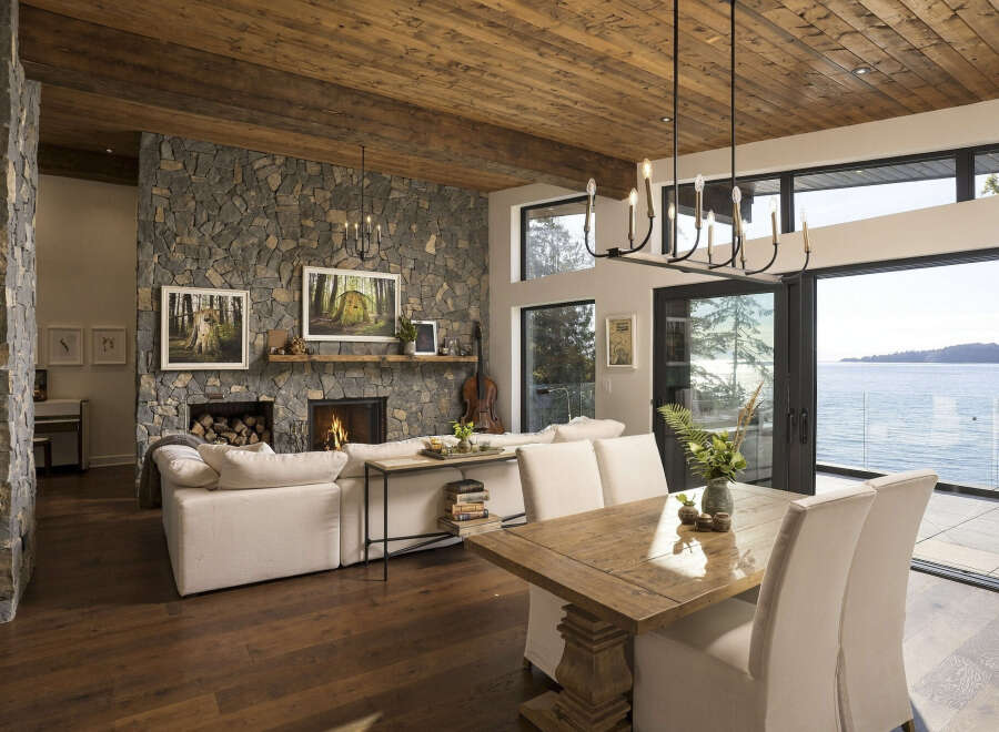 Experience luxurious lakeside living in this stunning home featuring a grand stone fireplace and a rustic wood-paneled ceiling.