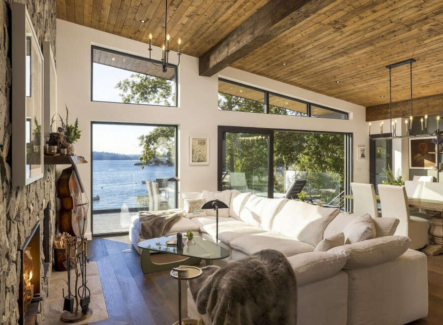Experience breathtaking waterfront living in this stunning modern home, featuring expansive windows that flood the space with natural light and offer panoramic views of the serene lake.