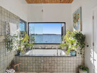 Experience ultimate relaxation in this stunning bathroom featuring a deep soaking tub with a breathtaking panoramic view of the water.