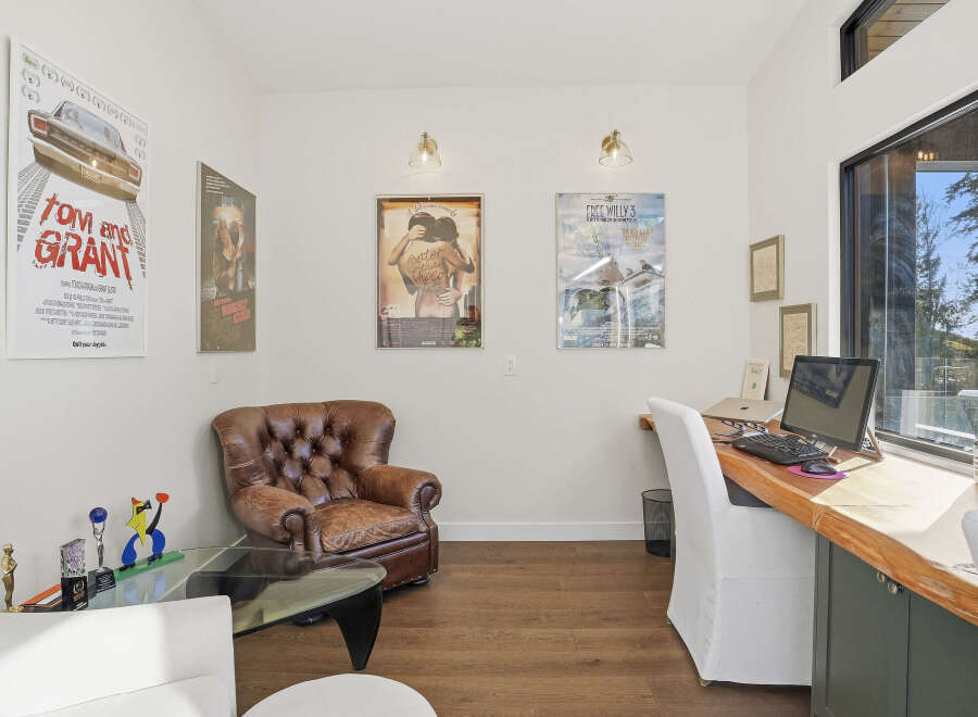 This home office features a comfortable leather armchair and a spacious wooden desk with a computer setup, perfect for productivity.