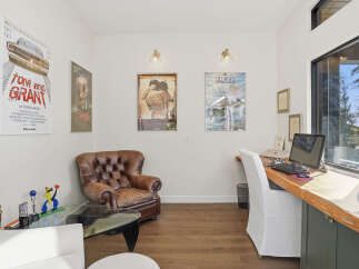 This home office features a comfortable leather armchair and a spacious wooden desk with a computer setup, perfect for productivity.