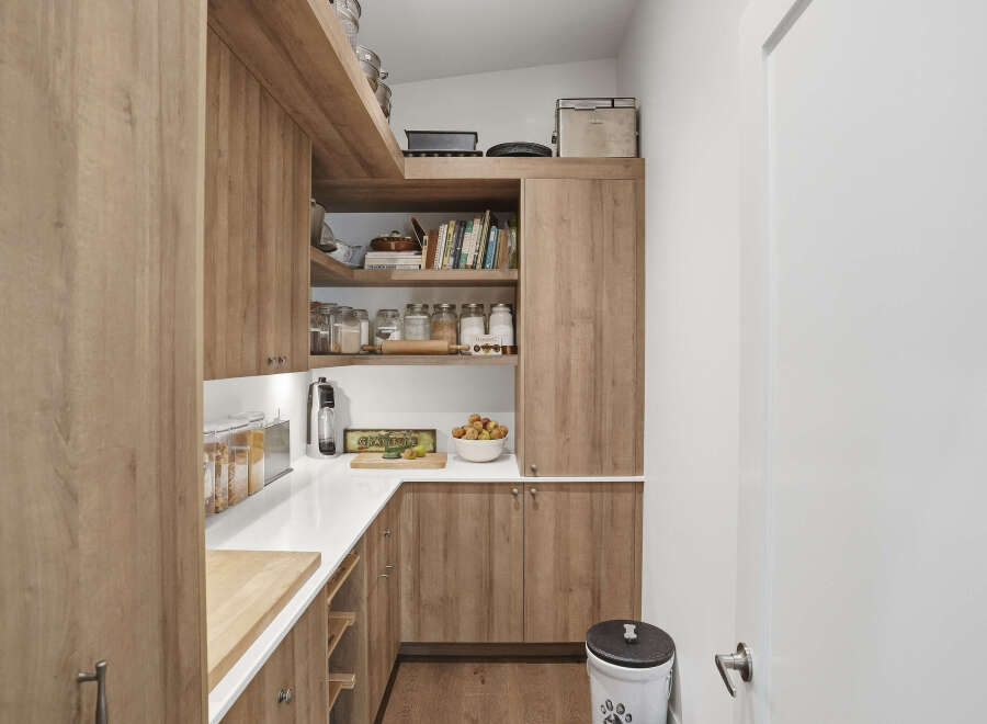 Discover this beautifully organized pantry, featuring warm wood cabinetry and ample shelving for all your storage needs.