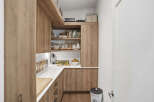 Discover this beautifully organized pantry, featuring warm wood cabinetry and ample shelving for all your storage needs.