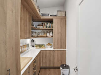 Discover this beautifully organized pantry, featuring warm wood cabinetry and ample shelving for all your storage needs.