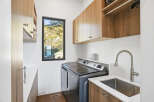 This modern laundry room features a sleek Maytag washer and dryer set, complemented by ample wood cabinetry for storage.