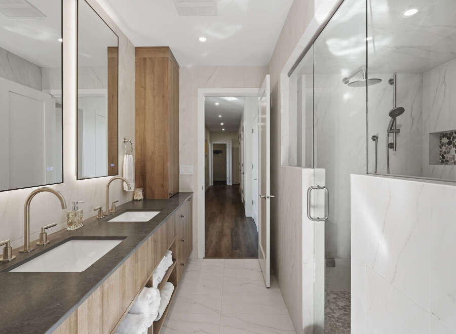 Experience luxury in this modern bathroom featuring a spacious double vanity with sleek faucets and ample storage.
