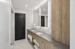 This modern bathroom features a sleek double vanity with a concrete-look countertop and warm wood cabinetry.