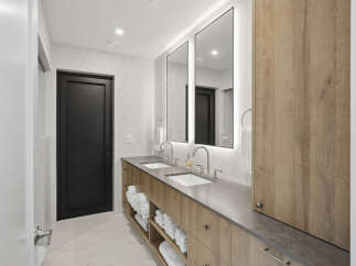This modern bathroom features a sleek double vanity with a concrete-look countertop and warm wood cabinetry.