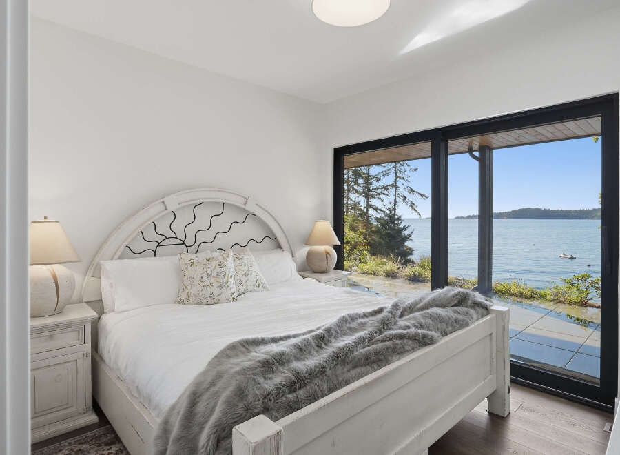 Experience breathtaking ocean views from this serene bedroom, featuring a comfortable king-sized bed adorned with a plush grey throw.