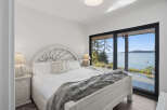 Experience breathtaking ocean views from this serene bedroom, featuring a comfortable king-sized bed adorned with a plush grey throw.