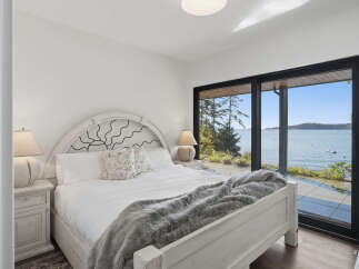 Experience breathtaking ocean views from this serene bedroom, featuring a comfortable king-sized bed adorned with a plush grey throw.