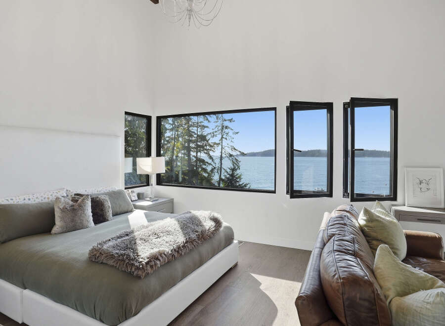Experience breathtaking ocean views from this luxurious bedroom, featuring a spacious king-size bed adorned with plush pillows and a cozy throw.