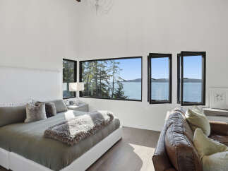 Experience breathtaking ocean views from this luxurious bedroom, featuring a spacious king-size bed adorned with plush pillows and a cozy throw.
