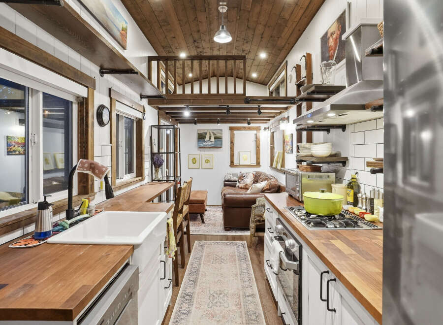 Experience cozy living in this charming tiny home, featuring a well-equipped kitchen with butcher block countertops and a gas range, perfect for culinary adventures.