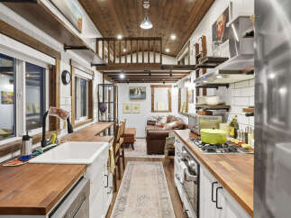 Experience cozy living in this charming tiny home, featuring a well-equipped kitchen with butcher block countertops and a gas range, perfect for culinary adventures.