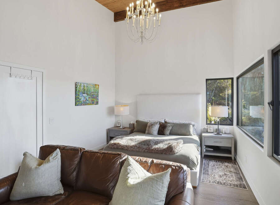 Experience modern comfort in this spacious bedroom, featuring a plush king-sized bed with a sleek white headboard and luxurious bedding.