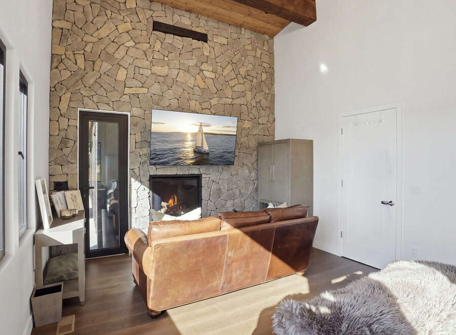 Experience rustic elegance in this living room, featuring a striking floor-to-ceiling stone fireplace that serves as the focal point.