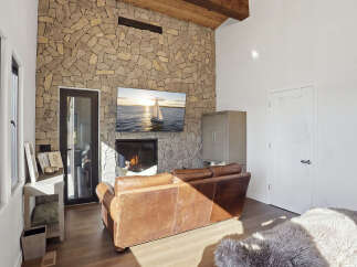Experience rustic elegance in this living room, featuring a striking floor-to-ceiling stone fireplace that serves as the focal point.