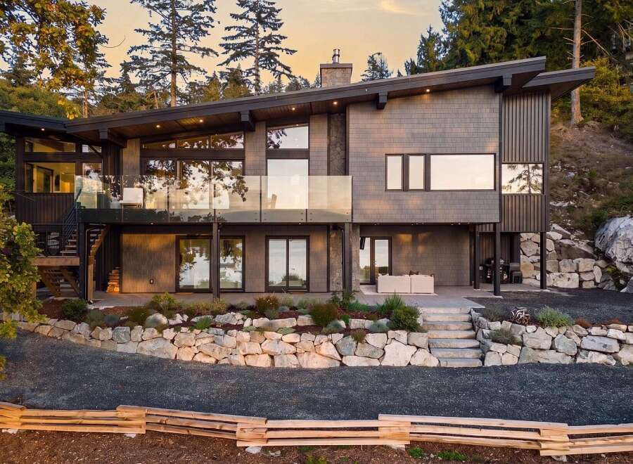 Experience modern luxury in this stunning hillside home, featuring expansive glass windows and a sleek, contemporary design.