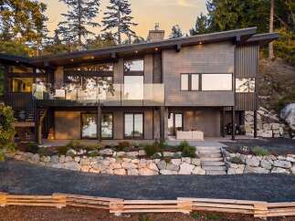 Experience modern luxury in this stunning hillside home, featuring expansive glass windows and a sleek, contemporary design.
