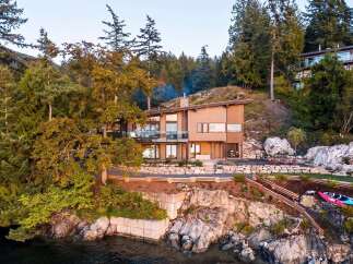 Experience luxury living in this stunning modern home nestled amidst lush trees and rocky shores.